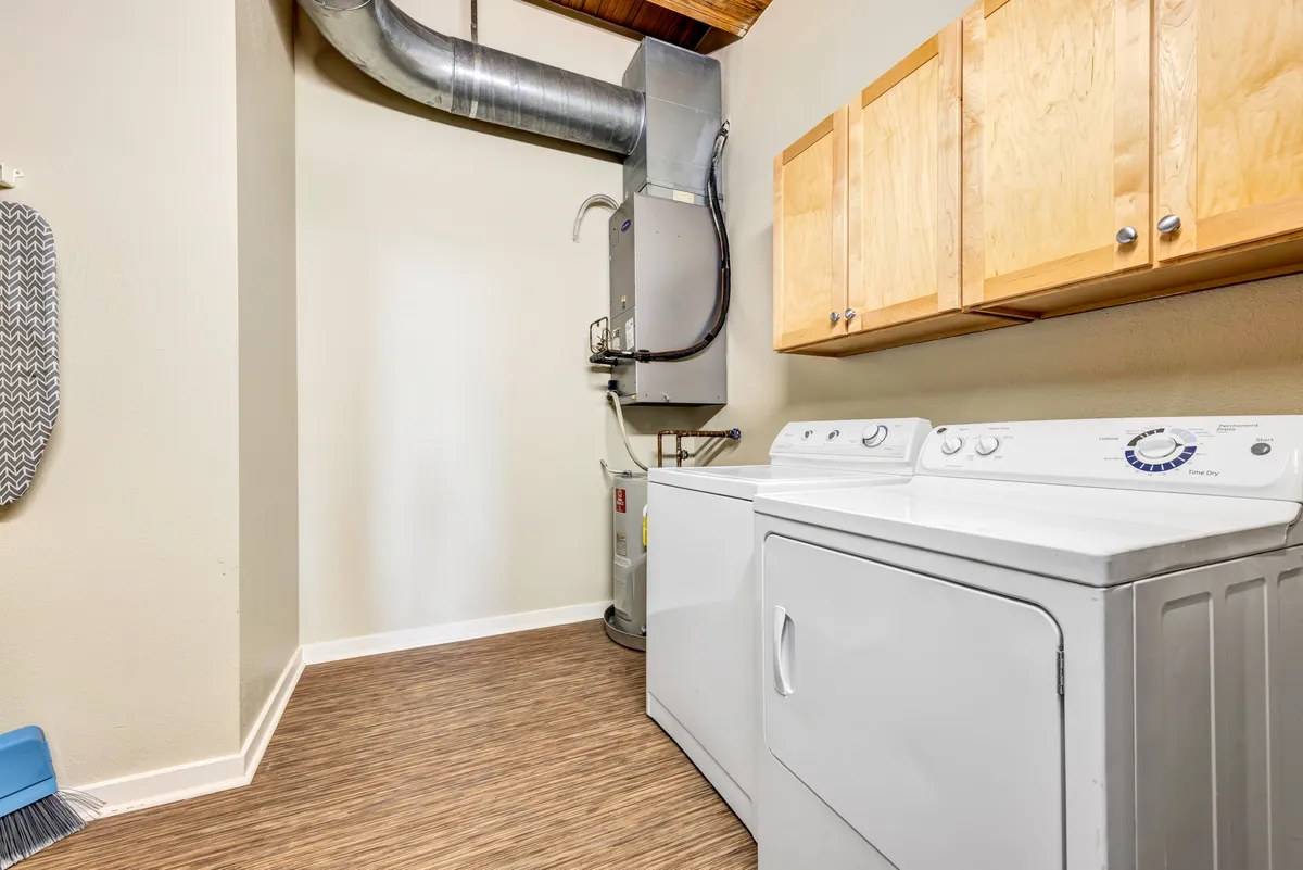 A dedicated laundry space featuring a washing machine and dryer set beneath sleek wooden cabinets. The area is organized and functional, with easy access to laundry supplies and a tidy appearance that speaks to convenience and thoughtful design.