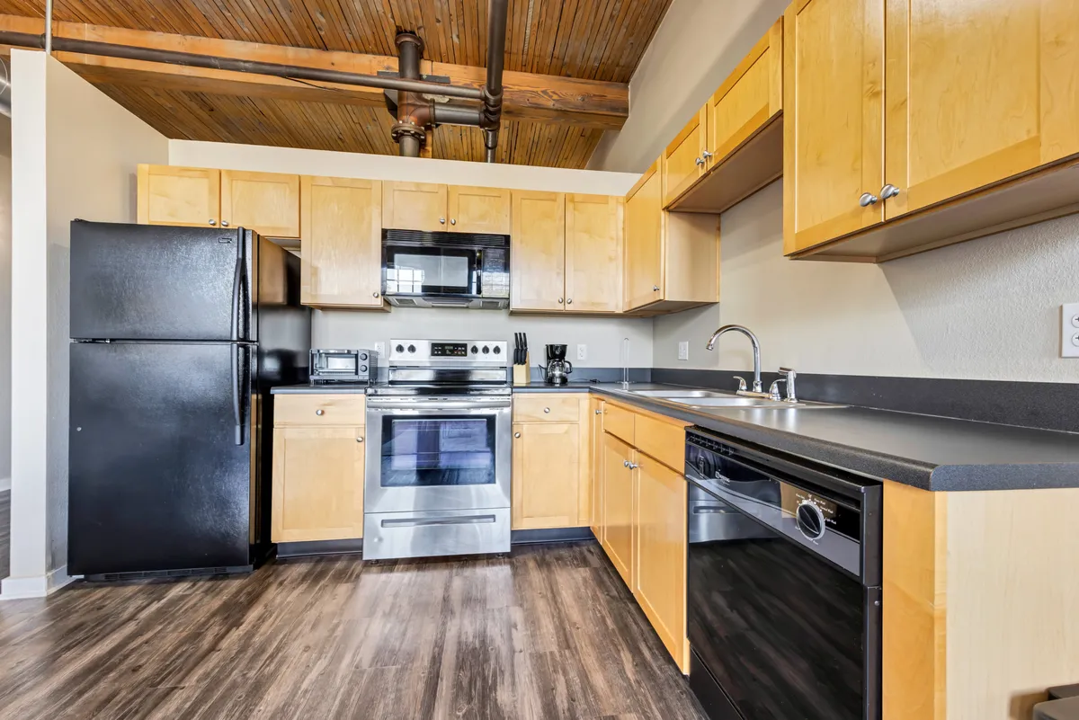 A modern kitchen with stainless steel appliances, wooden cabinetry, and an open layout designed for both cooking and entertaining. The scene suggests family gatherings or casual brunches, with a functional yet stylish ambiance. The appliances and cabinetry convey the fully equipped nature of the kitchen.