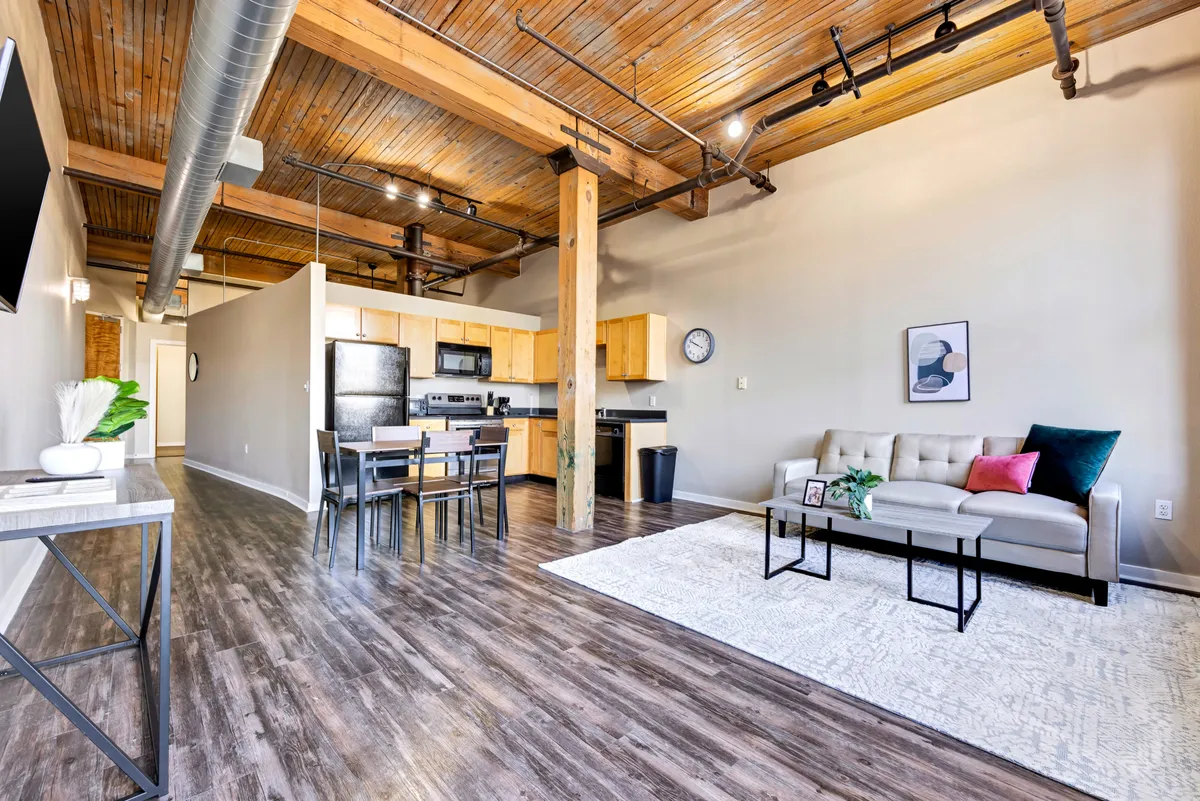 An inviting open-plan area featuring a cozy sofa, a dining table ideal for gatherings, and a modern kitchen. Decorative touches and a stylish rug add warmth, while the layout suggests a space perfect for hosting friends before heading out to explore the city.