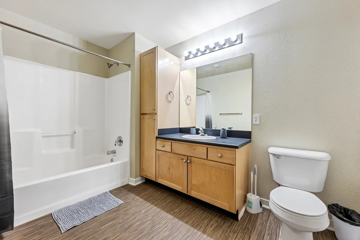 Modern bathroom with a sleek vanity and mirror, spacious bathtub, and an elegant shower area. The ambiance is inviting and functional, perfect for both quick morning routines and relaxing evening baths.